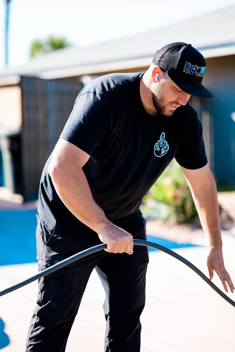 Black Pearl Pest Control technician treating the exterior of an Arizona home